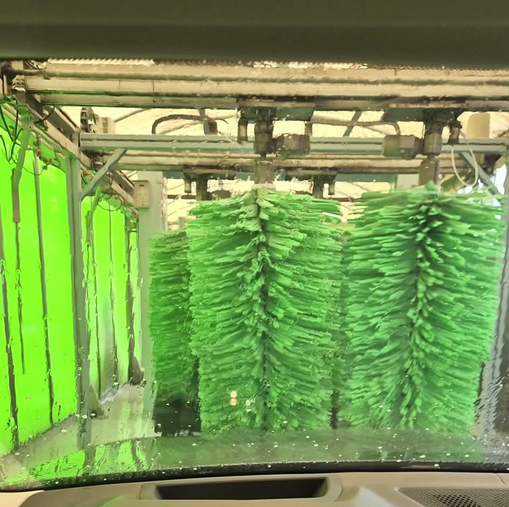 Coche dentro del túnel de lavado entre cepillos verdes